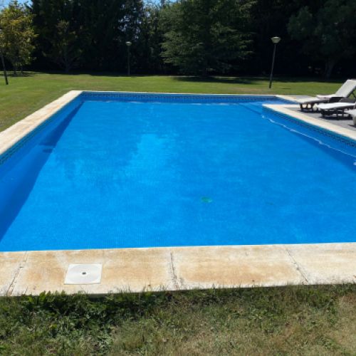 Imagen de piscina en terreno ajardinado con tumbonas a los lados
